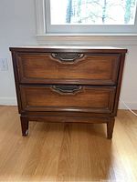 Front view of wooden side table showing two drawers with brass handles and wood grain finish.