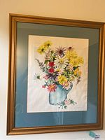 Full view of the framed watercolor painting featuring a colorful floral bouquet in a blue vase, with a blue-green mat and gold-tone wooden frame.