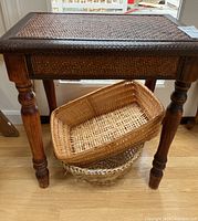 Full view of wooden side table with woven rattan-style top and two woven baskets underneath
