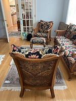 View of the chair backs showing the cane weave and wood frames with floral cushion.