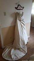 Full view of antique white wedding gown showing the long train and smooth fabric drape.