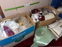 Photo showing three boxes containing lace, ribbons, and trims with mixed colors including white, cream, burgundy, and green satin ribbons.