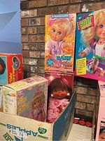 Boxed assortment of four dolls against brick background
