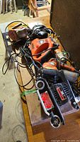 View of assorted sanders, jigsaws and stapler on table showing cords and some wear.