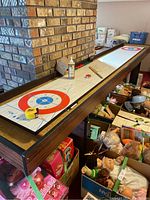 Full-length view of shuffleboard board showing woodgrain surface and printed scoring zones