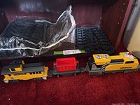 Overview photo showing the full train set including engine, freight car, caboose, and track pieces still in bags on a shelf.