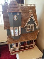 Exterior view of Victorian style doll house showing turret, bay window, and wood shingle roof