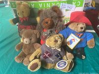 Overview of 5 assorted vintage teddy bears including plaid pant bear, shaggy brown bear, medium brown bear, Brass Button Bear, and Paddington Bear