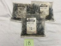 Four sealed plastic bags containing blue-grey tin roof screws marked 10x1-1/2 with bonded washers.