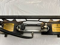 Top close-up of burner controls and propane hose connection, showing the labels and knobs.