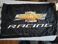 Full view of black Chevy Racing flag with large gold Chevrolet emblem and white 'RACING' text.
