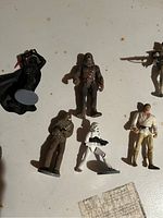 Photo showing Darth Vader, two Chewbacca figures, Stormtrooper, and Luke Skywalker action figures on white surface.