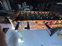 Side view of foosball table showing the colorful Sportscraft branding, player rods, and handles.