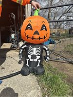 Photo of the inflated Halloween decoration showing the pumpkin head with skeleton body outside on grass.