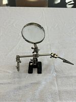 Front angled view showing the magnifying glass with two clips and black base on a white surface.
