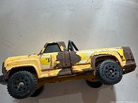 Side view of the vintage yellow Tonka steel pickup truck showing rust and paint chipping.