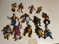 Lot of vintage Ninja Turtles and G.I. Joe action figures displayed on white surface.
