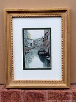 Framed watercolour painting showing Venetian canal scene with gondolas and buildings.
