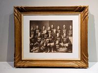 Framed antique rugby team photo showing the wood frame with carved details and the matte that surrounds the photo inside the frame.