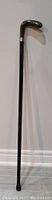 Full length photo of antique walking stick showing straight shaft and curved handle at top.