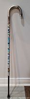 Full view of antique walking stick with silver curved handle and decorated shaft.
