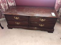 Front view of wooden blanket box with faux drawer fronts and brass pulls, showing surface wear.