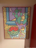 Full view of the colorful abstract painting showing cactus, tomatoes, and geometric figures with a red wooden frame.