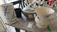 Photo of four pottery pieces on countertop including the tall floral vase, the covered tureen, and two urns with dragonfly motifs.