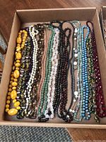 Wide view of multiple beaded necklaces arranged side by side showing color and style variety