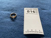 Ring on blue cloth next to MaxSold lot identification card
