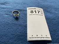 Ring on blue fabric with MaxSold notes and measurements card