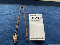 Pendant and chain laid out on blue felt alongside MaxSold tag