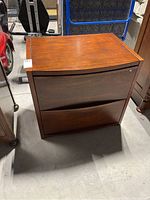 Front view showing the cabinet with two drawers, lock on top drawer, and veneer finish.