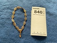 Bracelet laid flat next to lot measurement card showing number