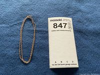 10 karat gold double chain bracelet laid on blue fabric next to MaxSold lot tag number 847.