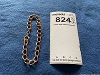 Bracelet laid out on blue felt next to MaxSold notes