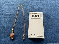 Full view of gold chain with pendant alongside measurement card