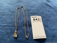 Necklace laid out on blue fabric with MaxSold tag.