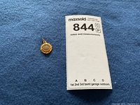 Pendant next to MaxSold lot tag on blue felt