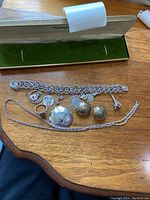 Full view of silver jewelry: charm bracelet with 8 charms, clip-on earrings, twisted chain necklace, and ring