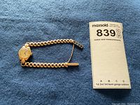 Full view of watch laid flat showing hexagonal case, chain link bracelet and safety chain