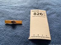 Brooch and maxsold tag on blue fabric