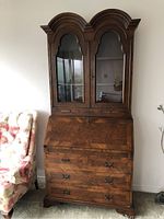 Full view of maple veneer secretary desk with glass cabinets on top, drop-front desk, and three drawers below