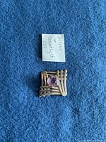 Silver pendant with amethyst gemstone on blue cloth background, with note indicating value $150
