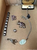 Top-down view of entire lot in cardboard, shows all seven jewelry pieces