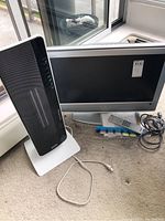 Sony Bravia 32-inch TV with remote control and heater placed nearby on carpeted floor next to window.