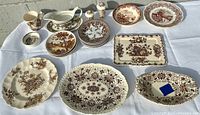 Overhead photo showing entire set arranged on white cloth, including various plates, platter, cups, gravy boat, and tray all in brown and white ceramic with patterns