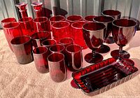 All ruby red glassware items displayed together including tumblers, goblets, and trays.