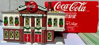 Front view of Coca-Cola Bottling Plant with red Coca-Cola sign and holiday wreaths, with original box in background