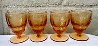 Front view of the 4 apricot pink colored Cornflower etched glass stemware pieces.
